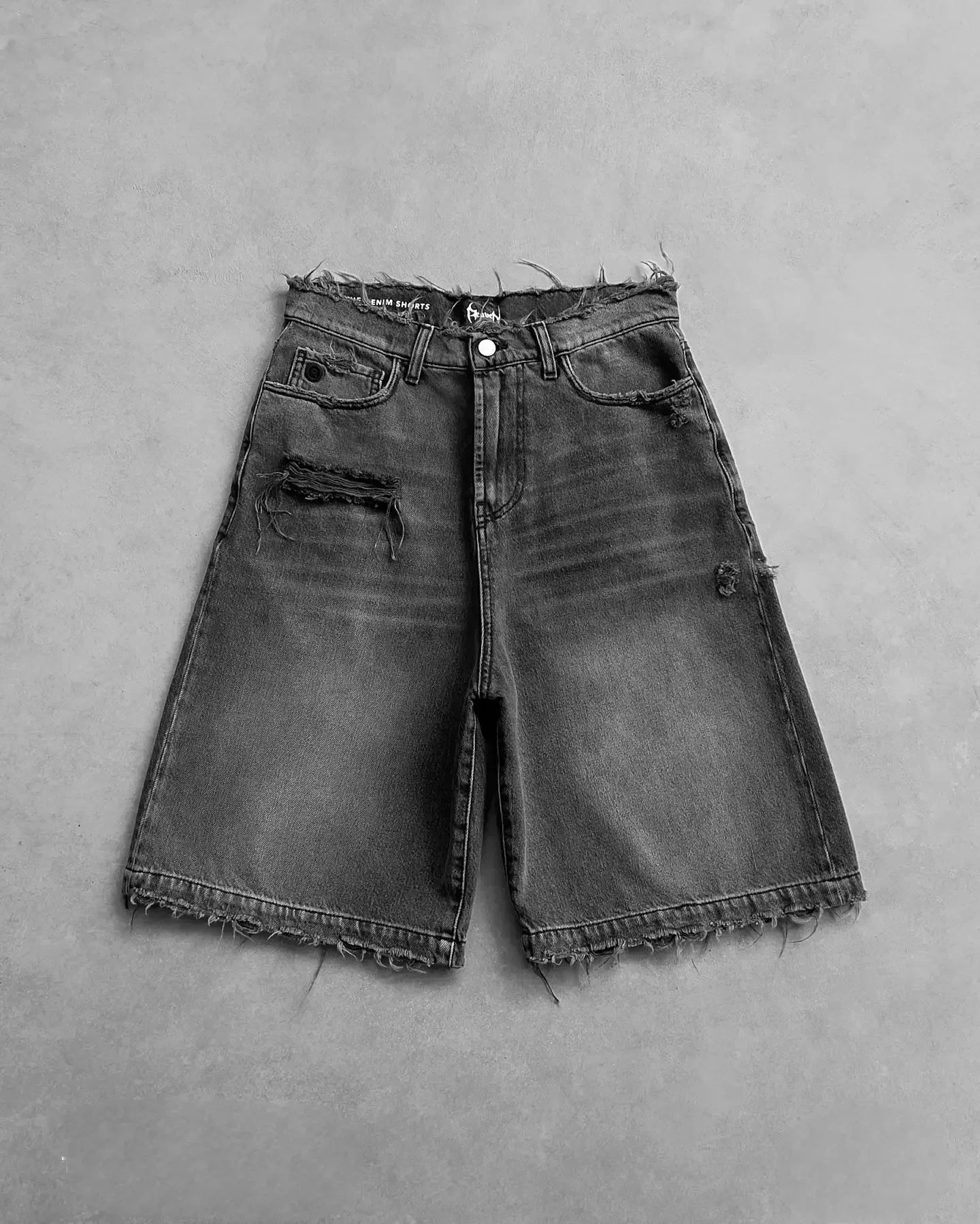 Vintage denim shorts with distressed details and frayed hem, styled on a hanger showcasing classic blue denim.